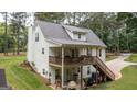 Rear elevation view of a white, two-story house featuring an upper deck with stairs to a concrete patio at 10 Stagg Trce, Social Circle, GA 30025