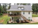Back of a two-story white house with upper deck, outdoor stairs, and a lower level outdoor living space at 10 Stagg Trce, Social Circle, GA 30025