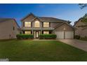 Charming two-story brick home with a well-manicured lawn, black shutters, and a two-car garage at 907 Brisley Cir, Hampton, GA 30228