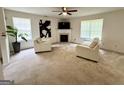 Bright living room with neutral carpet, fireplace, ceiling fan, and two large windows offering ample natural light at 105 Avonwood Cir, Locust Grove, GA 30248