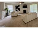 Bright living room with neutral carpet, fireplace, ceiling fan, and two large windows offering ample natural light at 105 Avonwood Cir, Locust Grove, GA 30248
