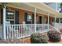 Inviting front porch with rocking chairs, brick accents, and views of the landscaped yard at 500 Hayfield Ct, Locust Grove, GA 30248