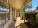 Inviting front porch with brick columns, sconce lighting, and a view of the landscaped yard at 137 Nobility Ln, Mcdonough, GA 30252