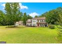 A wide shot of a two-story home with manicured front lawn and mature trees, and a bright red front door at 355 Sturgess Run, Sharpsburg, GA 30277