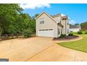 Attached two-car garage with a long driveway, beautiful landscaping, mature trees, and a fenced backyard at 355 Sturgess Run, Sharpsburg, GA 30277