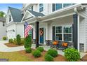 Inviting front porch with seating, decorative wreath, and an American flag by the door at 8 Saint Charles Ave, Sharpsburg, GA 30277