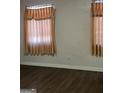 Bedroom with tan walls, dark wood floors, and beige curtains hanging over a window at 953 South Ave, Forest Park, GA 30297