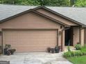 Attached two-car garage of a ranch home with landscaping and potted plants at 6884 Shangrila Way, Riverdale, GA 30296