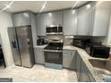 Modern kitchen featuring stainless steel appliances, gray cabinets, and sleek countertops at 6884 Shangrila Way, Riverdale, GA 30296
