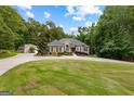 Expansive front yard featuring a circular driveway leading to a charming home nestled among lush trees and greenery at 285 Spear Rd, Peachtree City, GA 30269