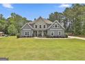 Beautifully designed home showcasing stone accents, a manicured lawn, and a welcoming entrance with seating at 33 Vinery Ct, Sharpsburg, GA 30277