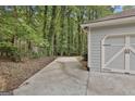 Long concrete driveway leads to a two-car garage with a wooded area visible beyond the garage at 505 Bracken Edge, Peachtree City, GA 30269