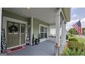 Inviting covered front porch with swing, American flag, and decorative touches at 100 Rabbits Run, Fayetteville, GA 30214