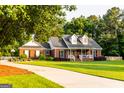 Charming brick home featuring a covered front porch and lush green lawn with mature trees at 30 Carolyn Ct, Social Circle, GA 30025