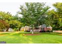 Charming brick home featuring a covered front porch and lush green lawn with mature trees at 30 Carolyn Ct, Social Circle, GA 30025