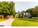 Charming brick home featuring a covered front porch and lush green lawn with mature trees at 30 Carolyn Ct, Social Circle, GA 30025