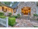 Stone front porch with iron railing, manicured landscaping, and double doors with sidelights create a welcoming entrance at 223 Old Rome Rd, Kingston, GA 30145