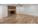 Bright living room with a brick fireplace, modern ceiling fan, and light wood floors at 90 Country Roads Cir, Stockbridge, GA 30281
