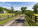 A long private driveway passes a red building, mature trees, lush green lawns, and black fencing at 110 Green Meadow Ln, Fayetteville, GA 30215