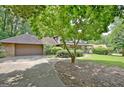 Home exterior with a long driveway, two-car garage, and a beautiful tree at 212 Garret Rdg, Peachtree City, GA 30269