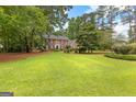 Sprawling front lawn leads up to a stately two-story brick home with lush trees at 108 Summit Walk, Peachtree City, GA 30269