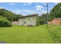 Spacious backyard showing the house and lush greenery, with some lawn equipment visible at 3570 Keels Ln, Atlanta, GA 30349