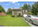 View of the two-story home with lush lawn and trees in background, two parked cars, and a glimpse of the roof at 3570 Keels Ln, Atlanta, GA 30349