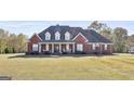 Stately brick home featuring dormer windows, a covered front porch, and a sprawling front lawn at 395 W Mcintosh Rd, Brooks, GA 30205