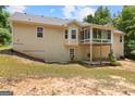 View of home's back exterior with screened porch, partially-finished basement, and wooded lot at 225 Chinns Way, Hampton, GA 30228