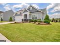 Charming gray home featuring a well-manicured lawn, landscaping, and a two car garage at 411 Southbridge Pass, Peachtree City, GA 30269