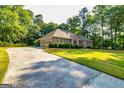 Long driveway leading to an attached garage and a beautiful brick home surrounded by lush greenery at 195 Youngs Cir, Fayetteville, GA 30215