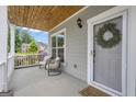 Inviting front porch with comfortable seating, wood ceiling, and charming wreath at 206 Roundwood Way, Peachtree City, GA 30269