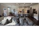 Open concept living and kitchen area with a large gray sofa and a kitchen with white cabinets and island at 442 Snow Owl Way, Lawrenceville, GA 30044