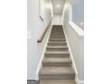 Carpeted stairway with white trim and a wooden handrail leading to the upper level of the home at 1317 Rosemary Ln # 65, East Point, GA 30344