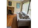 Cozy living room with a stone fireplace, a comfortable couch, and natural light illuminating the hardwood floors at 5094 Covington Hwy, Decatur, GA 30035