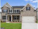 Charming two-story home featuring a two-car garage, neutral brick, and manicured lawn at 3468 Jasmine Sw Way, South Fulton, GA 30331