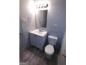 Bathroom featuring a single sink vanity, mirror, toilet, and wood-look flooring at 187 Peyton Sw Pl, Atlanta, GA 30311