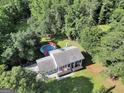 Aerial view of home with pool, featuring a large lot surrounded by lush greenery and mature trees at 437 Mays Rd, Stockbridge, GA 30281