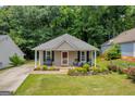 Charming tan home with a covered porch and well-maintained landscaping, nestled among lush trees at 136 Glynn Addy Dr, Stockbridge, GA 30281