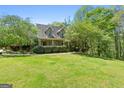 Traditional home with a large, lush front lawn, mature trees, and a welcoming covered porch at 1561 Aiken Chafin Ln, Mcdonough, GA 30252