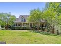 Inviting front exterior featuring a charming covered porch, a well-maintained lawn, and mature trees for added privacy at 1561 Aiken Chafin Ln, Mcdonough, GA 30252