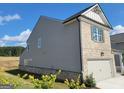 Side of gray vinyl siding and gray brick home featuring a two-car garage at 35 Fraser Ln # 123B, Auburn, GA 30011