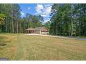 Lovely home on a large lot with a covered carport adjacent to the house, surrounded by lush trees at 55 Etheridge Rd, Temple, GA 30179