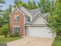 Two-story house featuring a brick facade, attached two-car garage, and manicured lawn with tree at 2576 Abbotts Glen Nw Dr, Acworth, GA 30101