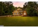 Charming two-story home at dusk featuring a manicured lawn and inviting curb appeal at 155 Carrolls Way, Fayetteville, GA 30215