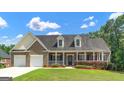 Charming brick home with a two-car garage, inviting front porch and lush landscaping at 185 Stewart Glen Dr, Covington, GA 30014