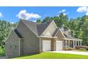 Side view of a brick home with a two-car garage, complemented by a green lawn and trees at 185 Stewart Glen Dr, Covington, GA 30014