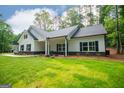 Attractive single-story home with black shutters, a lush green lawn, and pristine landscaping in a peaceful, wooded setting at 5525 Belle Meade Dr, Villa Rica, GA 30180