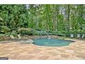 A kidney-shaped in-ground pool surrounded by a stone patio, lush landscaping, and mature trees at 505 Lighthouse Ln, Peachtree City, GA 30269