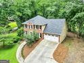 Aerial view of a brick and tan two-story home with a driveway, garage, and surrounded by lush trees at 135 Crimson Rdg, Tyrone, GA 30290
